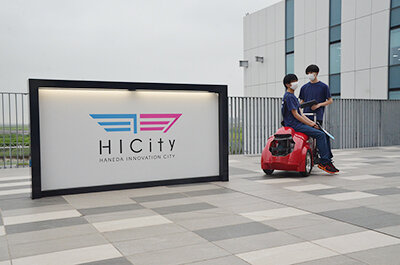 HICityの看板と学生と小型移動ロボット